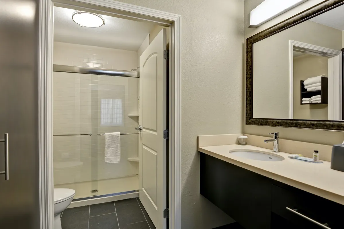 The image features a fresh, bright bathroom with a modern shower area, vanity with sink, and soft towels. The inviting mood suggests a rejuvenating experience, ideal for guests returning from outdoor activities seeking to refresh and unwind.