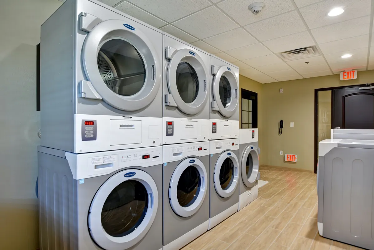 A practical laundry area with stacked washers and dryers, a laundry folding table, and clear signage, offering an efficient and convenient space for handling laundry needs. The setup is clean and organized, making it easy for guests to manage their laundry during extended stays.